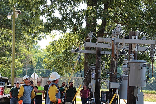 Lineworkers Wade Harris (above), and Gabe Dennis (upper left) demonstrate what a live line does to a hot dog. 